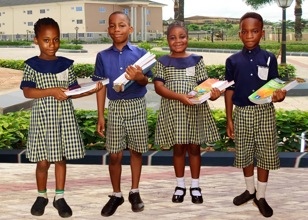 Four pupils in green check uniforms holding new exercise books