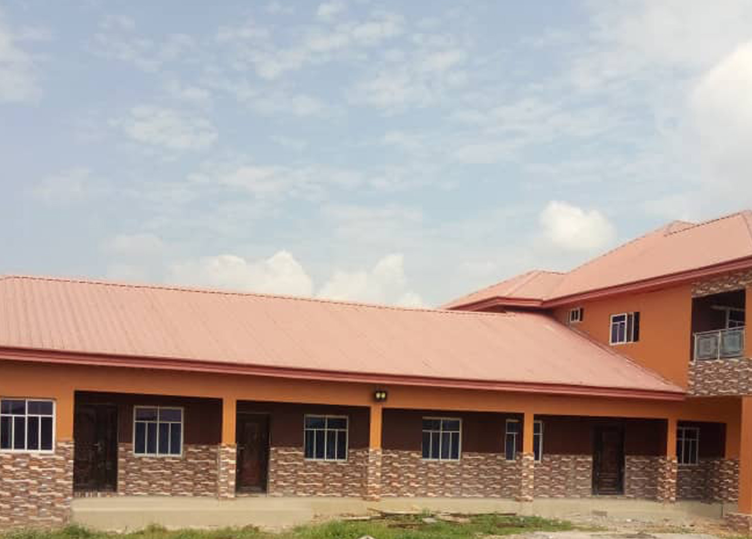 The single-storey school building with its terracotta roof under a wide sky