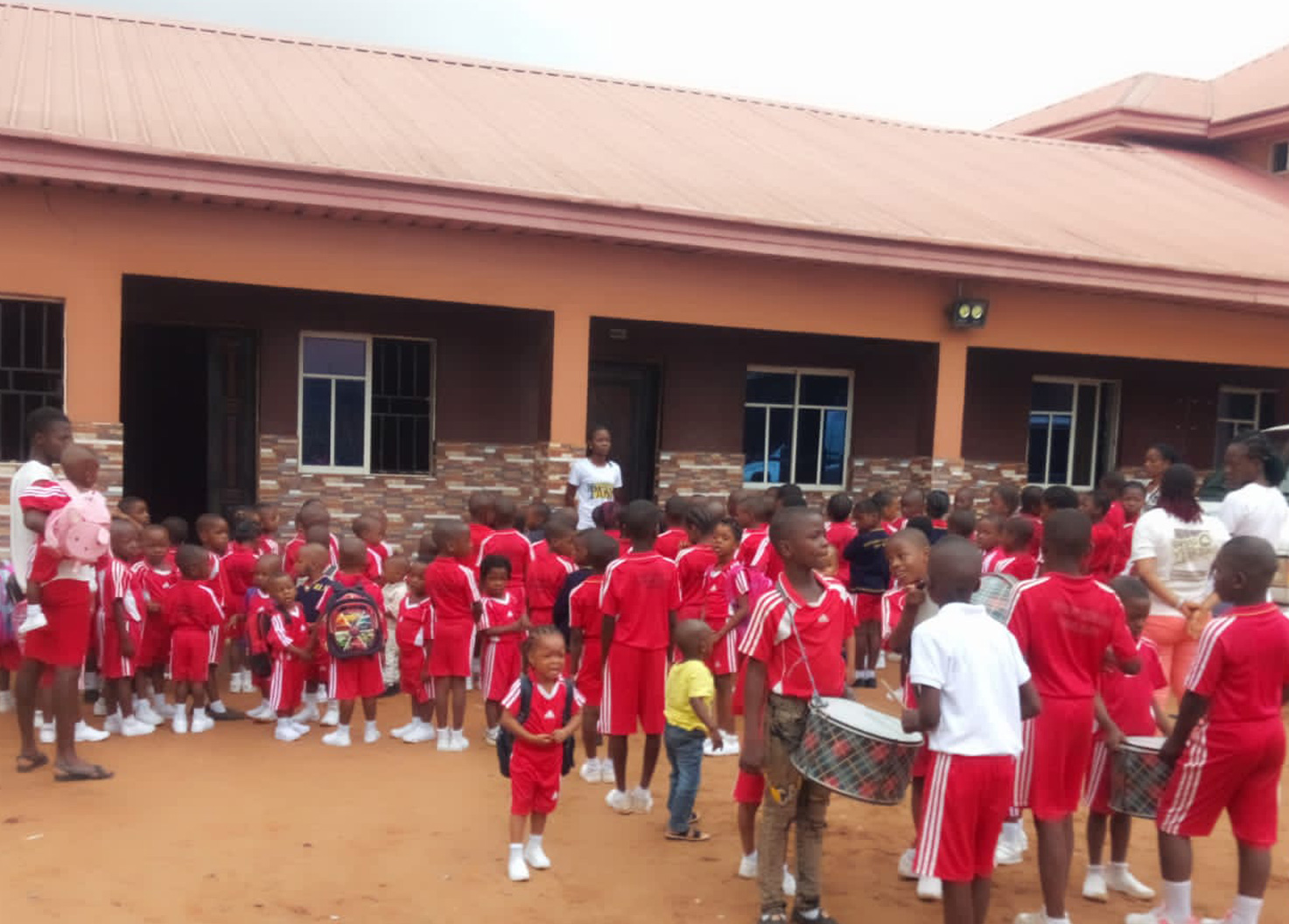 Pupils in red sports uniforms gathered in front of the school building
