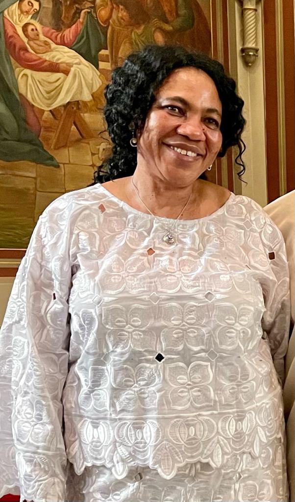 Mrs. Joy Ikanih, smiling, in a white embroidered blouse